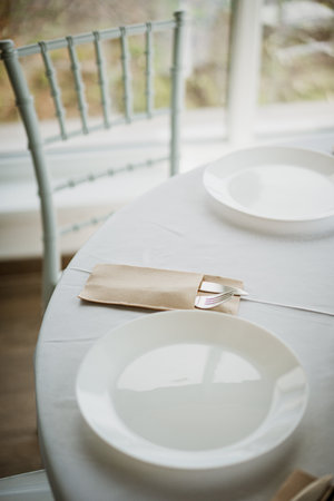 Romantic restaurant table setting with white plate and cutlery.