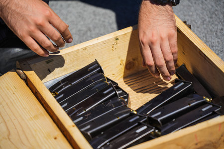 Hands reaching in an ammo box with rifle bullet magazines.