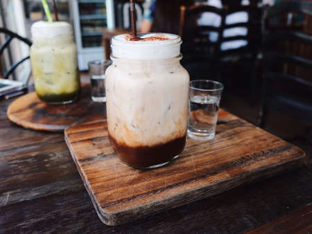 A glass of iced coffee on the wooden cutting boardの素材