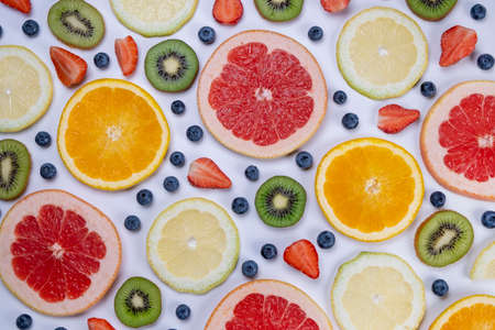 background of blueberries, strawberries, lemon, orange, grapefruit and kiwi slices on a white background - the concept of a healthy diet. Summer bright food fruit background, food designの写真素材