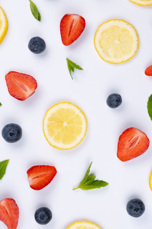 Vertical background of blueberries, strawberries, lemon slices and mint leaves on a white background...