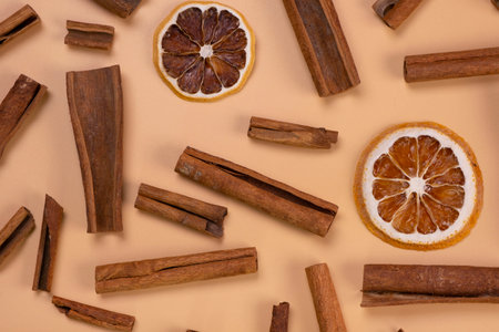 background with cinnamon sticks and dried lemon or orange slices on a beige background, cozy food, spicy trendy backgroundの写真素材