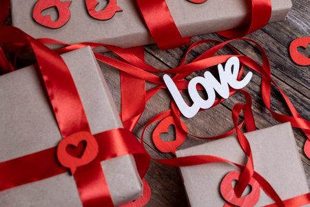 Valentines Day composition background with boxes, gifts, red ribbons and hearts and the inscription - Love on a wooden backgroundの写真素材