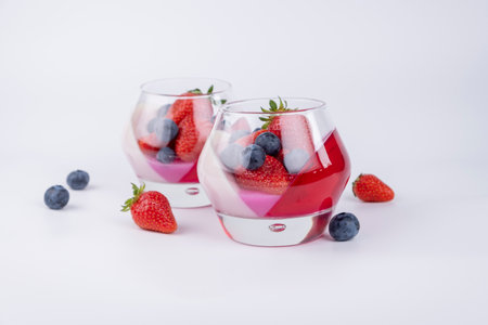 Fruit jelly dessert or panna cotta with fresh strawberries and blueberries, top view, banner, copy space, menu, template for texts on white backgroundの写真素材