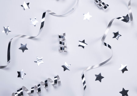 White background with a silver serpentine and stars. concept of celebrating a birthday,newborn , party or anniversary in silver tonesの写真素材