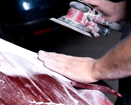 Worker is sanding filler with air sander in auto body shopの写真素材