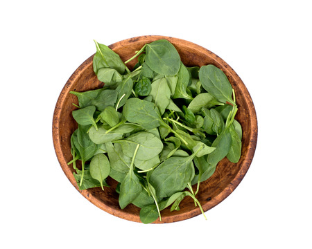 Spinach organic baby leaves in wooden bowl isolated on white backgroundの写真素材