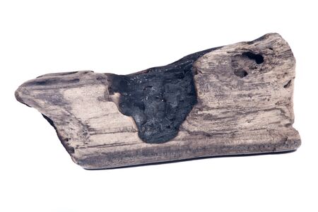 Partly burned charred piece of wood from beach isolated on white background