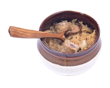 Traditional sour cabbage soup in ceramic bowl with wooden spoon isolated on white backgroundの写真素材