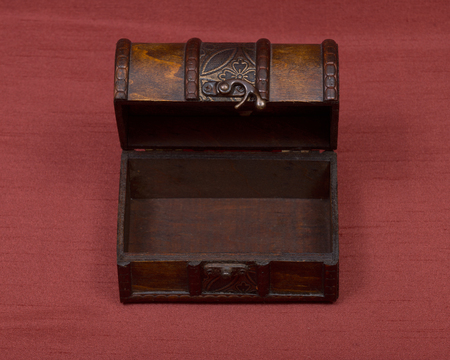 Wooden vintage jewelry box on red fabric background