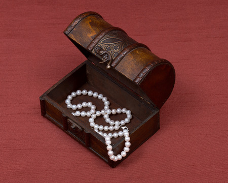 Wooden vintage jewelry box with freshwater white pearls necklace on red fabric backgroundの写真素材