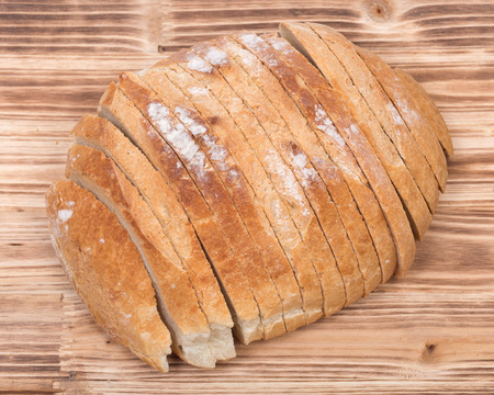 Sliced crusty country style round organic french bread isolated on wooden vintage tray