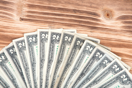 Fan of two dollar bills on vintage wooden background