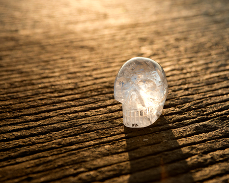 Clear quartz skull standing on the ground in front of rising sunの写真素材