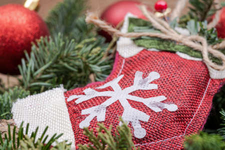 Winter holiday decoration: snowflake crochet Christmas stocking in the middle of a Fraser fir table wreath centerpiece with cones and juniper with Christmas tree balls on burlap backgroundの写真素材