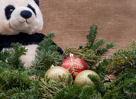 Winter holiday decoration: fraser fir table wreath centerpiece with cones, juniper, Christmas tree balls and panda bear stuffed plush toy on burlap backgroundの写真素材
