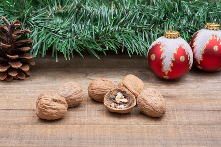 Winter holiday decoration: Blooming Red Poinsettia, Pine, Berry bush, Christmas tree balls, pine cone, walnuts and green garland on wooden background.の写真素材