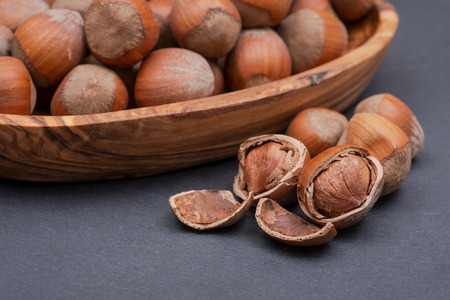Fresh organic high quality hazelnuts, filberts in wooden bowl on natural stone background.