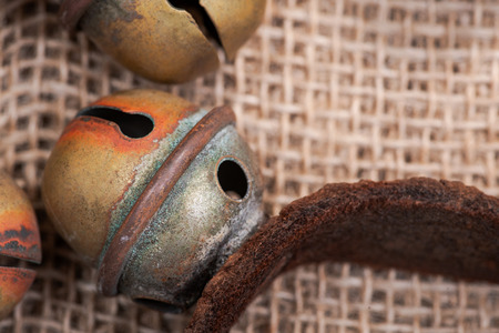 Antique vintage oxidize brass sleigh bells on leather strap and burlap background