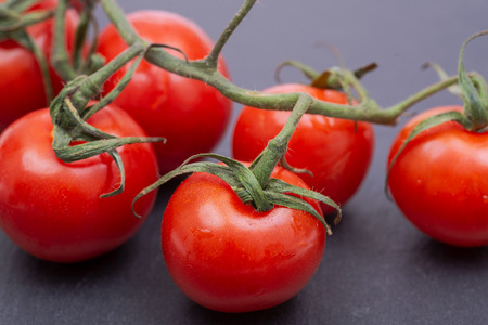 Organic red cherry tomatoes on the vine and and natural stone background.の写真素材