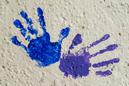Color hand prints painted on a white concrete wall.の写真素材