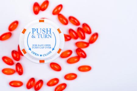Docusate sodium red capsules and plastic container with Child-Resistant Push&Turn Cap. Top view.