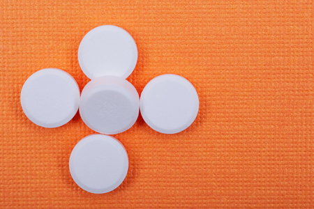 Non-steroidal anti-inflammatory drugs. Acetaminophen white tablets on orange background.の写真素材