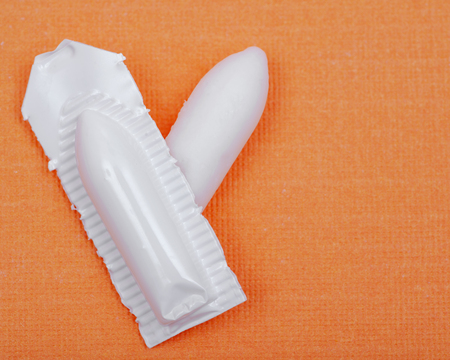 Medication in disposable plastic suppository moulds on orange background. Rectal drug administration