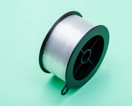 Premium quality clear monofilament fishing line in roll isolated on green background.の写真素材