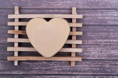Wooden Soap Holder with a Heart shaped Goat milk Soap on wooden background.の写真素材