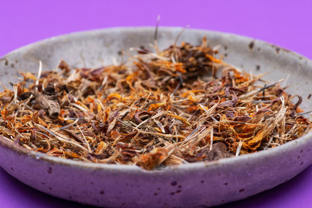 Marigold Dry Seeds (Mexican marigold, Aztec marigold, African marigold) in ceramic plate on purple...