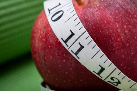 Red Apple and Soft Vinyl Measuring Tape on Green Yoga Mat.の写真素材