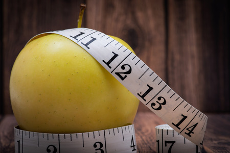 Yellow Apple and Soft Vinyl Measuring Tape on wooden background.の写真素材