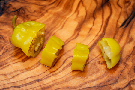 Pickled Golden Greek Peppers, Pepperoncini or Friggitelli (sweet Italian chili pepper) on natural olive wood cutting board . Capsicum annuum.の写真素材