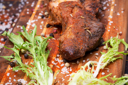 Oven Roasted Pork sprinkled  with spices and garnished with frisee endive leaves on wooden cutting board.の写真素材
