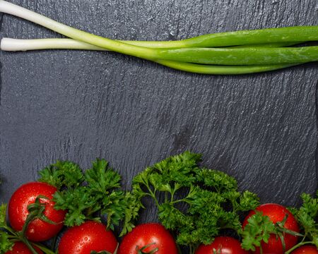 Organic Red Tomatoes on the vine, fresh Curly Parsley and Green Onion Scallions arranged on natural stone background.の写真素材