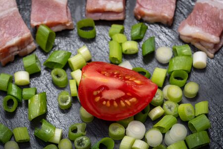 Uncured Apple Smoked Bacon, Red Tomatoes and Green Onion Scallions  arranged on black natural stone background.の写真素材