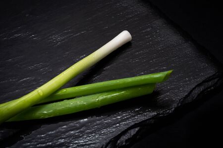 Organic Green Onion Scallions arranged on black natural stone background. Allium onion species.の写真素材