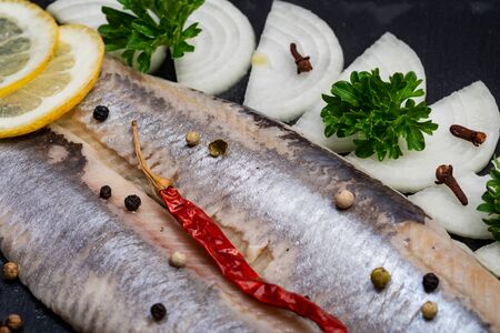 Salted Herring Fillets garnished with Yellow Onion, Lemon, Fresh Parsley and Dried Chili Pepper....
