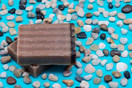 Handmade ultra-moisturizing Frankincense and Myrrh  Scented Goat's Milk Bar Soap decorated with small stone Pebbles on bright blue background.の写真素材