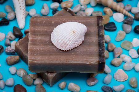 Handmade moisturizing Frankincense & Myrrh Goat's Milk Bar Soap decorated with small Pebbles, Sea Stars and Sea Shells on bright blue background.の写真素材
