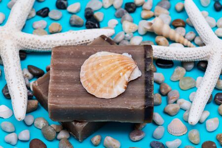 Handmade moisturizing Frankincense & Myrrh Goat's Milk Bar Soap decorated with small Pebbles, Sea Stars and Sea Shells on bright blue background.の写真素材