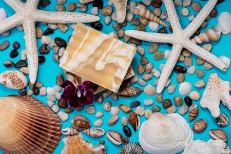 Handmade ultra-moisturizing Almond Scented Goat's Milk Bar Soap decorated with small Pebbles, Sea Stars and Sea Shells on bright blue background.の写真素材