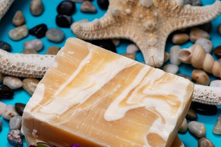 Handmade ultra-moisturizing Almond Scented Goat's Milk Bar Soap decorated with small Pebbles, Sea Stars and Sea Shells on bright blue background.の写真素材