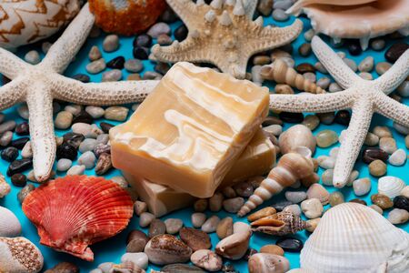 Handmade ultra-moisturizing Almond Scented Goat's Milk Bar Soap decorated with small Pebbles, Sea Stars and Sea Shells on bright blue background.の写真素材