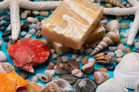 Handmade ultra-moisturizing Almond Scented Goat's Milk Bar Soap decorated with small Pebbles, Sea Stars and Sea Shells on bright blue background.の写真素材