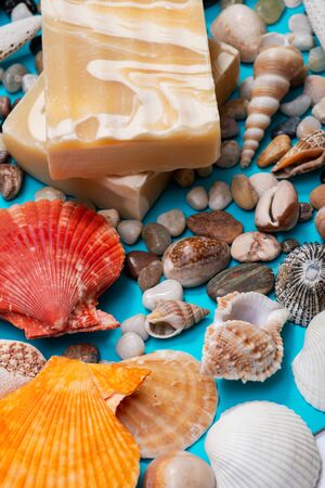 Handmade ultra-moisturizing Almond Scented Goat's Milk Bar Soap decorated with small Pebbles, Sea Stars and Sea Shells on bright blue background.の写真素材