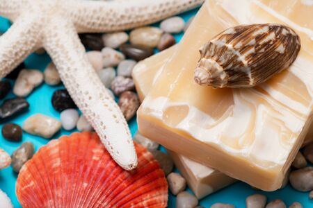 Handmade ultra-moisturizing Almond Scented Goat's Milk Bar Soap decorated with small Pebbles, Sea Stars and Sea Shells on bright blue background.の写真素材