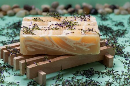 Wooden Soap Holder with Handmade ultra-moisturizing Almond Scented Goats Milk Bar Soap decorated with flower sprinkles confetti on green background.の写真素材