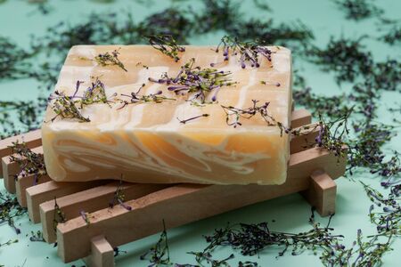 Wooden Soap Holder with Handmade ultra-moisturizing Almond Scented Goats Milk Bar Soap decorated with flower sprinkles confetti on green background.の写真素材